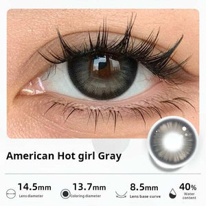 Close-up of an eye wearing "American Hot girl Gray" contact lenses, showing a bold, defined gray ring for a dramatic look. Specifications: 14.5mm diameter, 13.7mm graphic diameter, 8.5mm base curve, 40% water content.