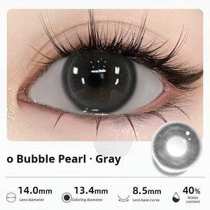 Close-up of an eye wearing "Bubble Pearl - Gray" contact lenses, presenting a deep, glossy dark gray tone. Specifications: 14.0mm diameter, 13.4mm graphic diameter, 8.5mm base curve, 40% water content.