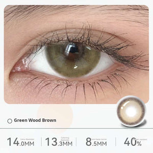 Close-up of an eye wearing "Green Wood Brown" contact lenses, displaying a subtle olive-green tint blended with brown. Specifications: 14.0mm diameter, 13.3mm graphic diameter, 8.5mm base curve, 40% water content.
