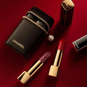 Luxurious lifestyle shot of CHANEL Pearl Pouch and lipsticks on a deep red background.