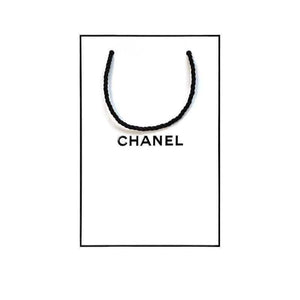 Iconic white CHANEL shopping bag with black logo for gift sets.