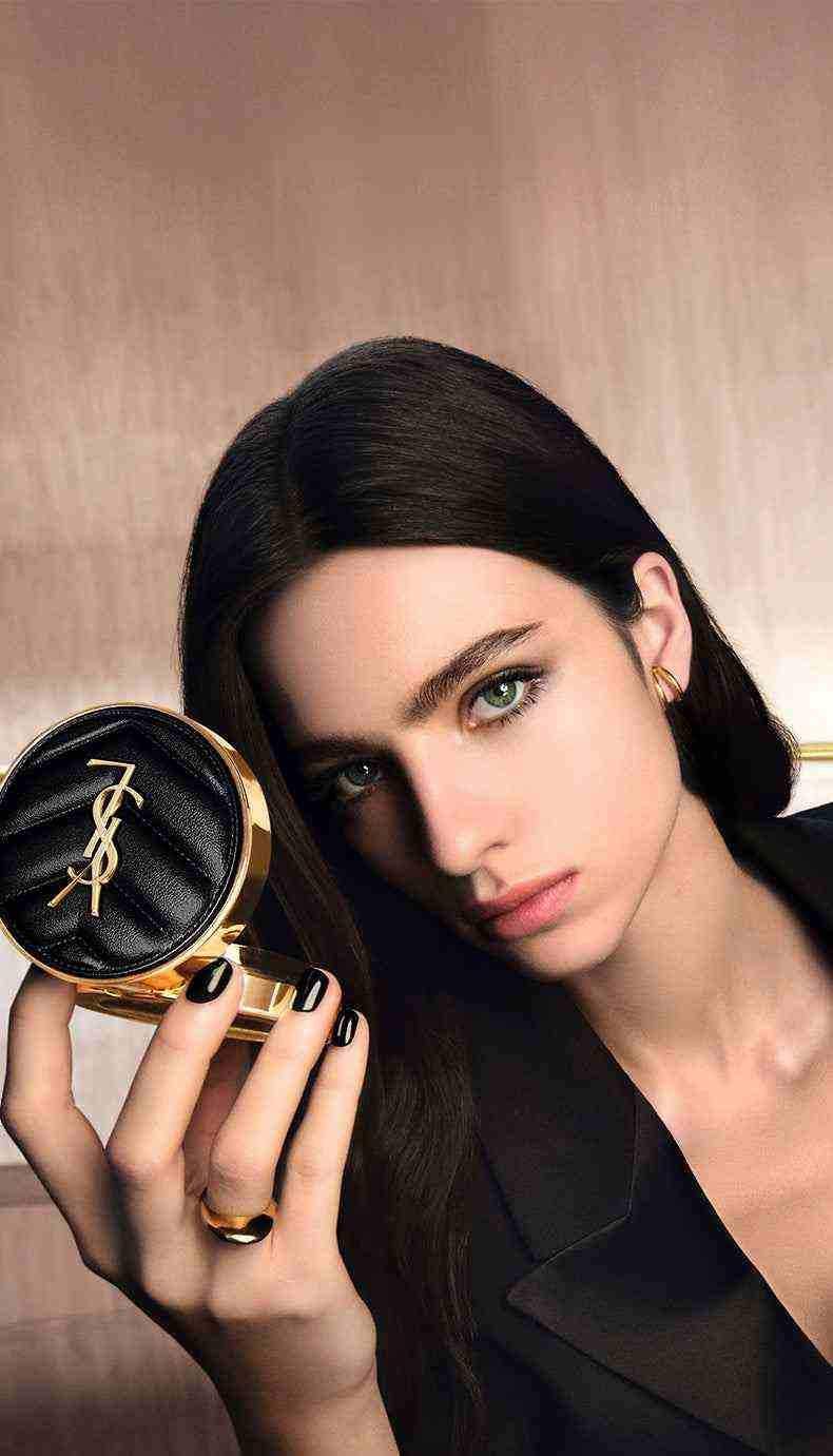 Elegant woman holding YSL Cushion Foundation compact showcasing luxury makeup product with natural radiant finish