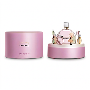 علبة عطر وردية بجانب الزجاجة مع حليات على منصة بيضاء
