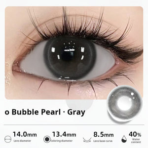 Close-up of an eye wearing "Bubble Pearl - Gray" contact lenses, presenting a deep, glossy dark gray tone. Specifications: 14.0mm diameter, 13.4mm graphic diameter, 8.5mm base curve, 40% water content.