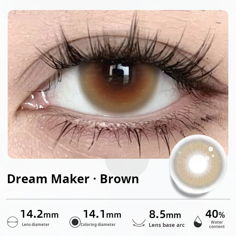 Close-up of an eye wearing "Dream Maker - Brown" contact lenses, featuring a warm hazel-brown center. Specifications: 14.2mm diameter, 14.1mm graphic diameter, 8.5mm base curve, 40% water content.
