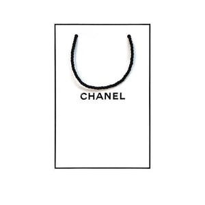 Iconic white CHANEL shopping bag with black logo for gift sets.