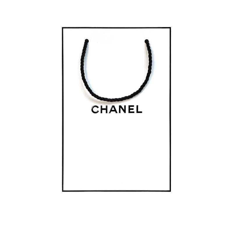Iconic white CHANEL shopping bag with black logo for gift sets.