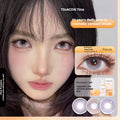 Promotional banner for Tinacon Tina cosmetic contact lenses, featuring a close-up of a woman with dark hair and large, luminous grey-purple eyes.